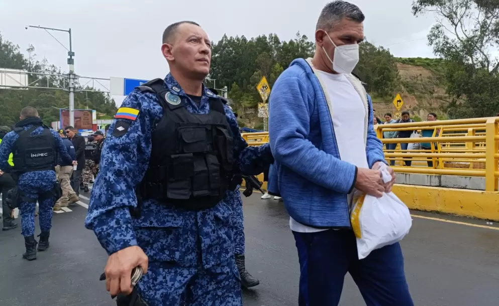 Un integrante del Instituto Nacional Penitenciario y Carcelario custodia a un hombre colombiano este mircoles, en Rumichaca (Ecuador).