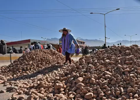 Una mujer pasa sobre un mont�culo de piedras, puestas por seguidores del expresidente Evo Morales, que bloquean una carretera en Cochabamba.