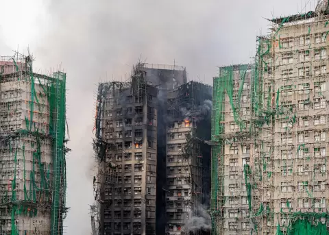 Una nube de humo sale del edificio de Hong Kong que sufri� un enorme incendio provocando la muerte de decenas de personas.