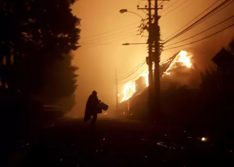 Una persona evacua un �rea de casas afectadas por los incendios forestales la madrugada de este domingo, en Penco (Chile).