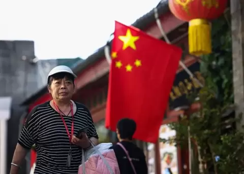 Fotograf�a de archivo de una mujer caminando con una bandera de China en el fondo.