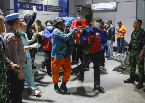 Rescatistas trasladan a una ambulancia el cuerpo de una v�ctima del letal choque de trenes en la estaci�n de tren de East Bekasi.