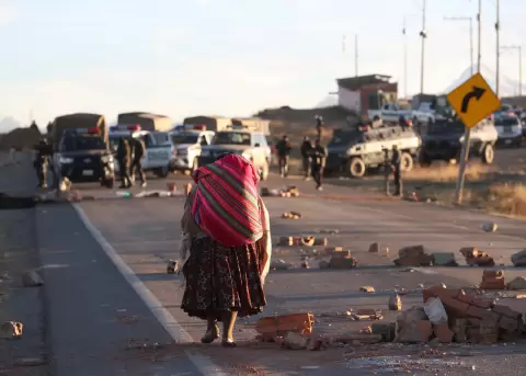 Una persona camina por una carretera bloqueada con escombros en Achica Arriba (Bolivia).