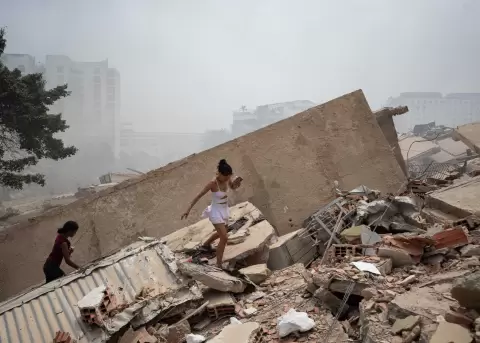 Personas caminan este jueves, entre los escombros de edificios afectados por los terremotos en La Guaira (Venezuela).