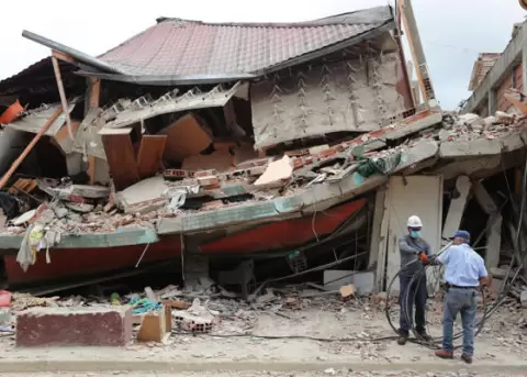 Hombres trabajan este s�bado, frente a una casa derrumbada por los terremotos en Venezuela