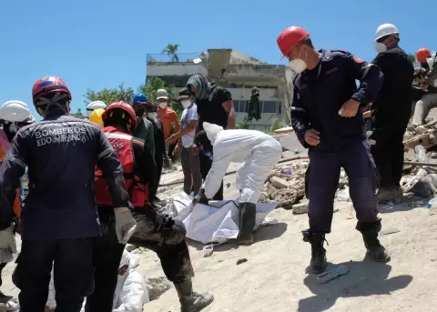 Bomberos y voluntarios rescatan un cuerpo sin vida durante los trabajos de remoci�n de escombros de los edificios Mision Vivienda OPPE en Venezuela.