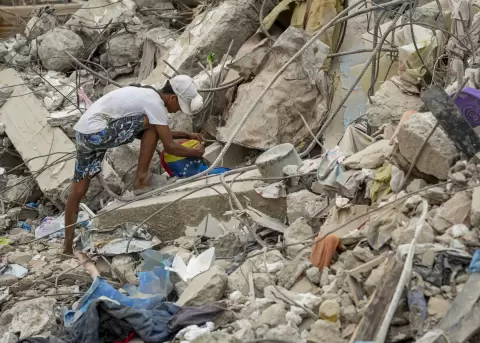 Una persona busca entre los escombros de edificios destruidos por terremotos en Caraballeda (Venezuela).
