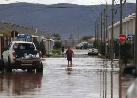 Una persona camina por una calle inundada por el desborde del Canal Bellavista, este lunes en el barrio Mirador de Hacienda, en La Serena (Chile).