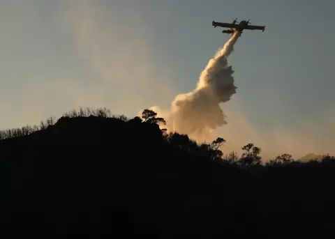 Un avi�n de extinci�n opera para sofocar un incendio forestal en la isla de Salamina, Grecia.